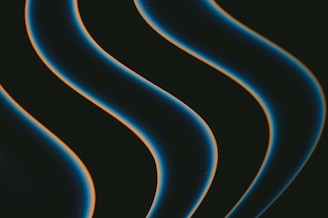 Dark, smooth, wavy lines with a glowing edge move diagonally across a black background. The lines have a blue hue with a hint of orange outlining.