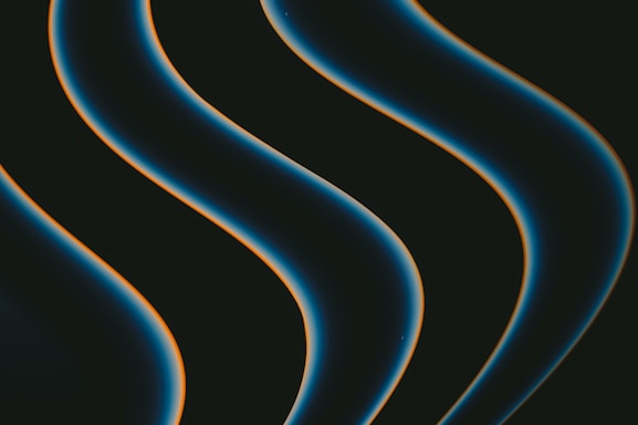 Dark, smooth, wavy lines with a glowing edge move diagonally across a black background. The lines have a blue hue with a hint of orange outlining.