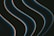 Dark, smooth, wavy lines with a glowing edge move diagonally across a black background. The lines have a blue hue with a hint of orange outlining.