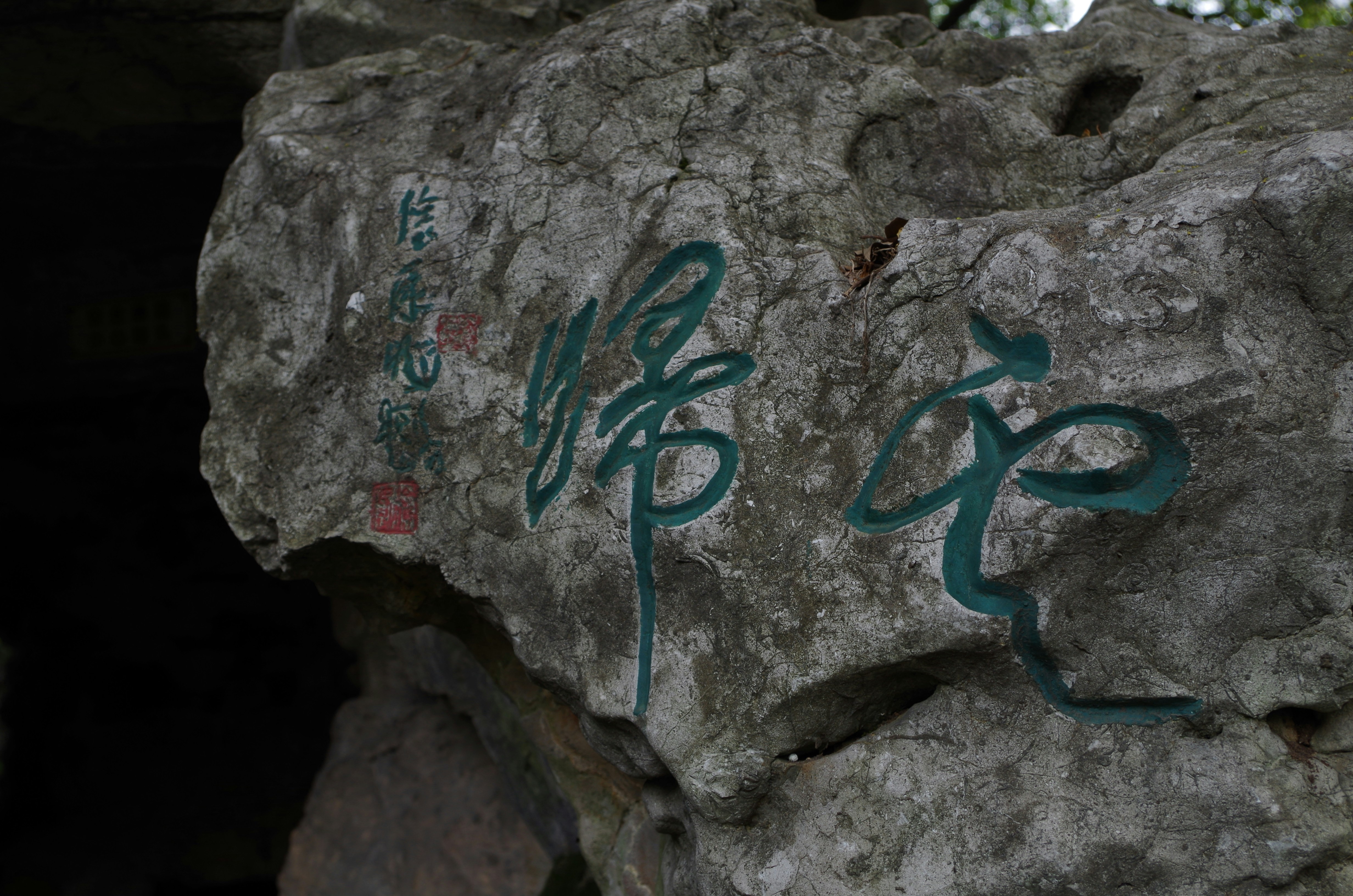 a rock with writing on it and a tree in the background