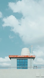 A sturdy blue water tank installed on a rooftop under a clear sky