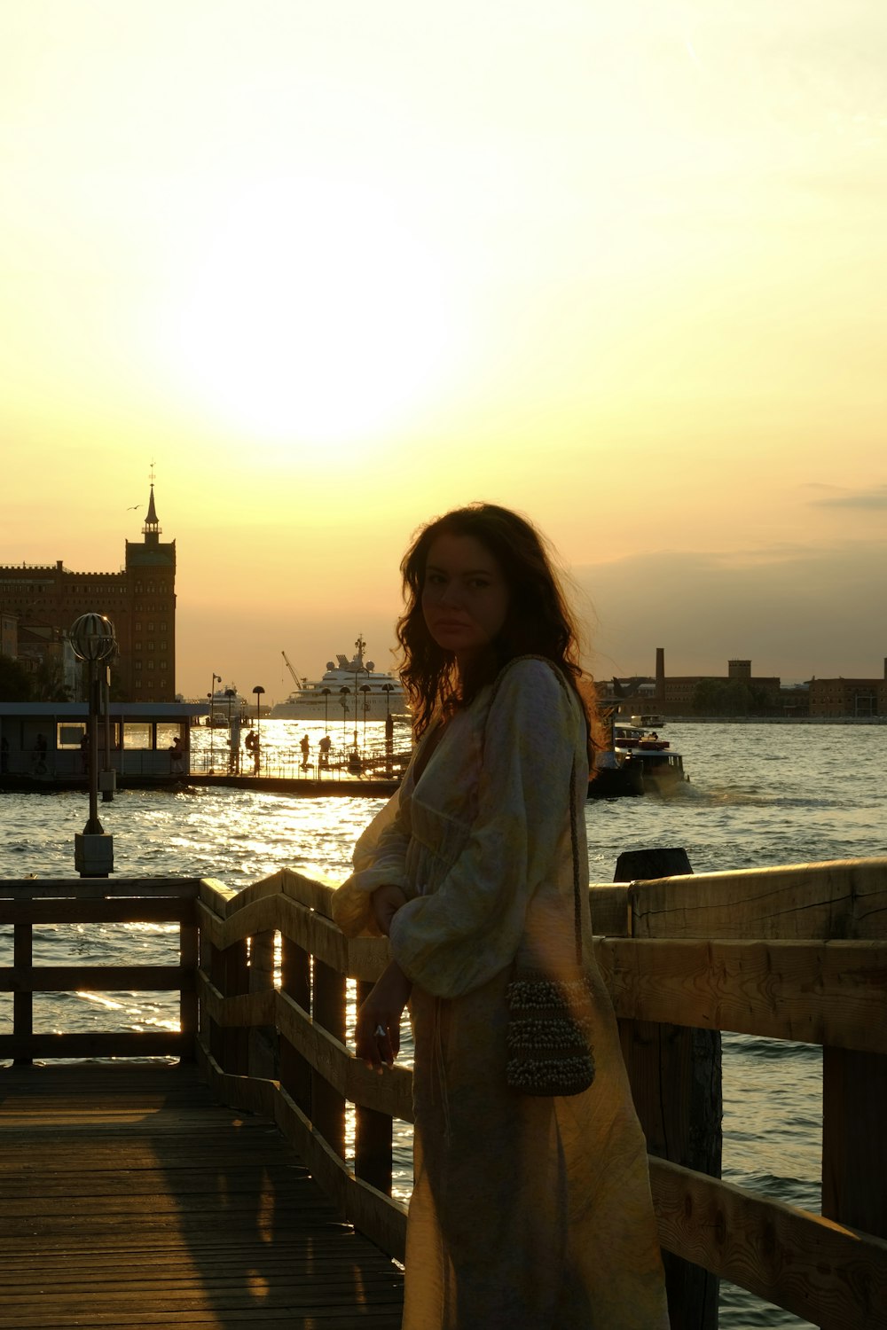 a woman standing on a pier at sunset