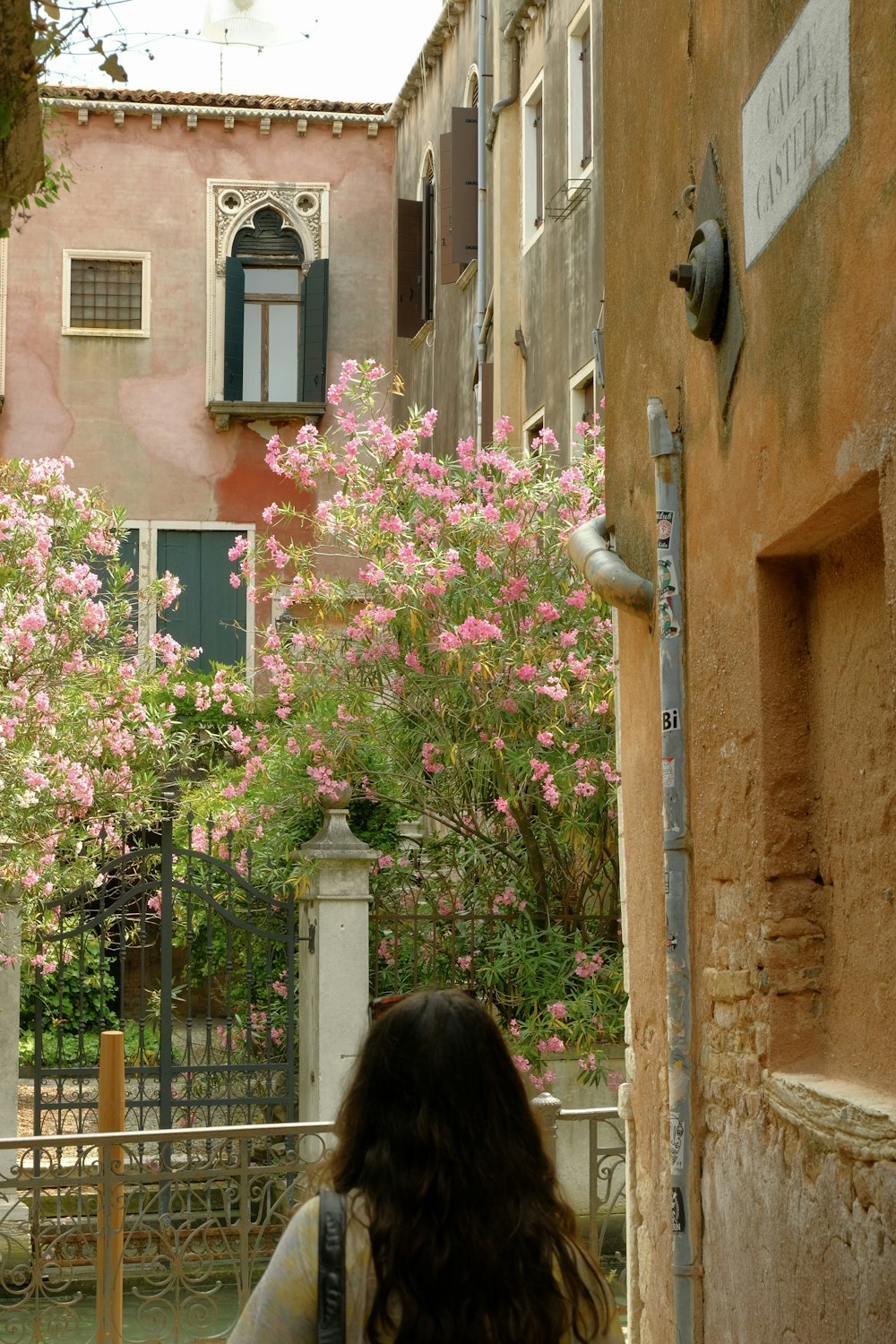 a woman walking down a street past tall buildings