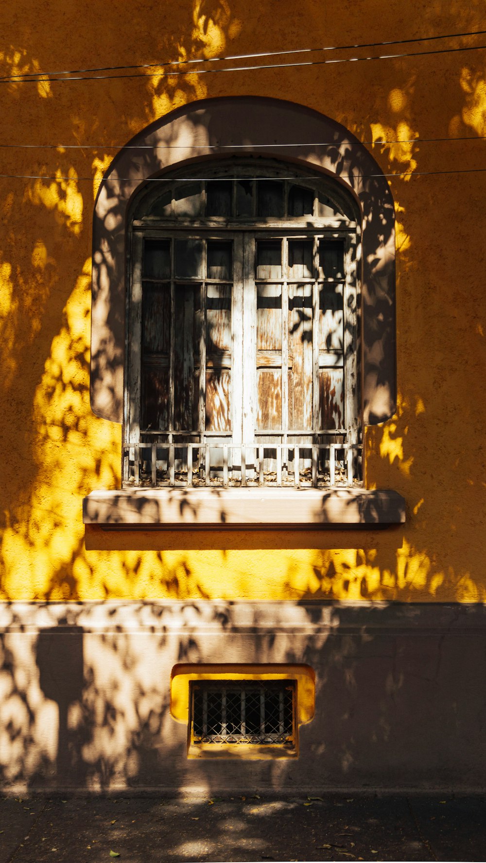 a yellow building with a window and bars