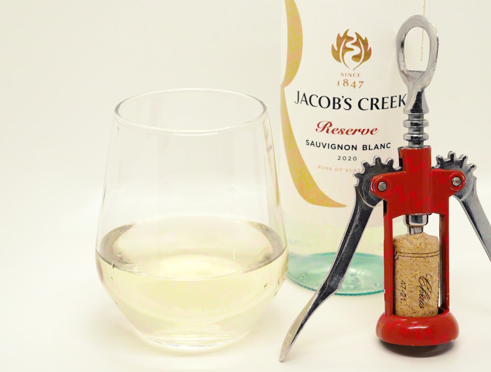 a corkscrew and a glass of wine next to a bottle