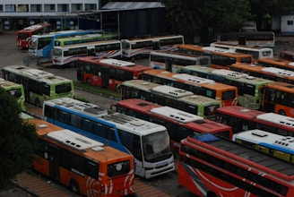 A fleet of buses lined up at a logistics hub with drivers preparing for departure.
