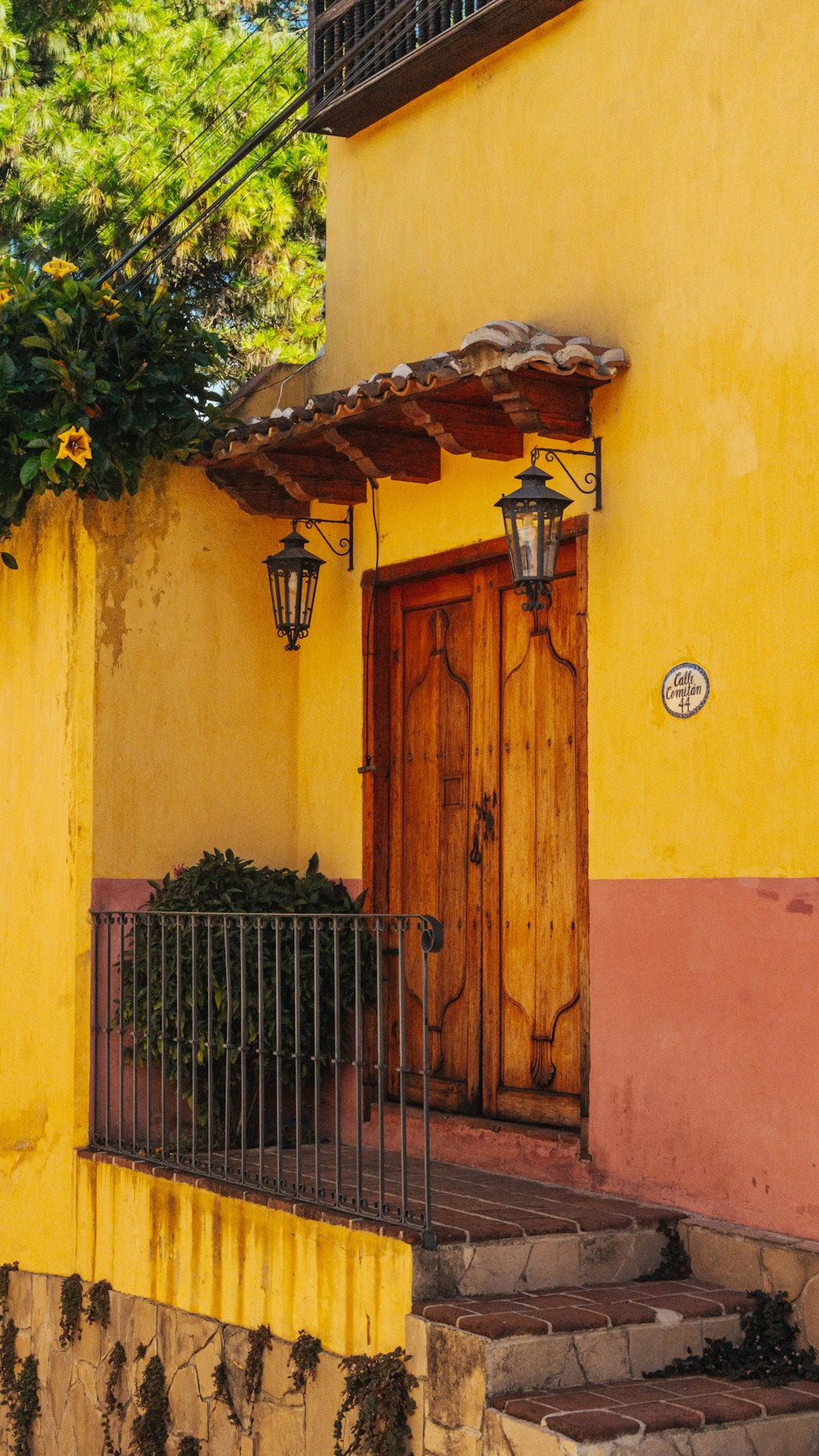 um edifício amarelo com uma porta de madeira e uma cerca de ferro forjado