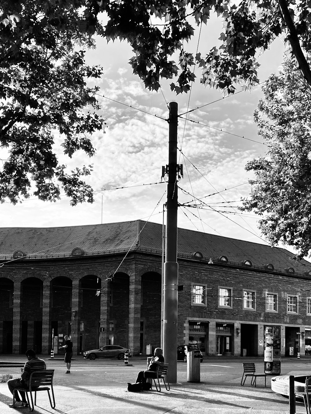 a black and white photo of people sitting on benches in front of a building