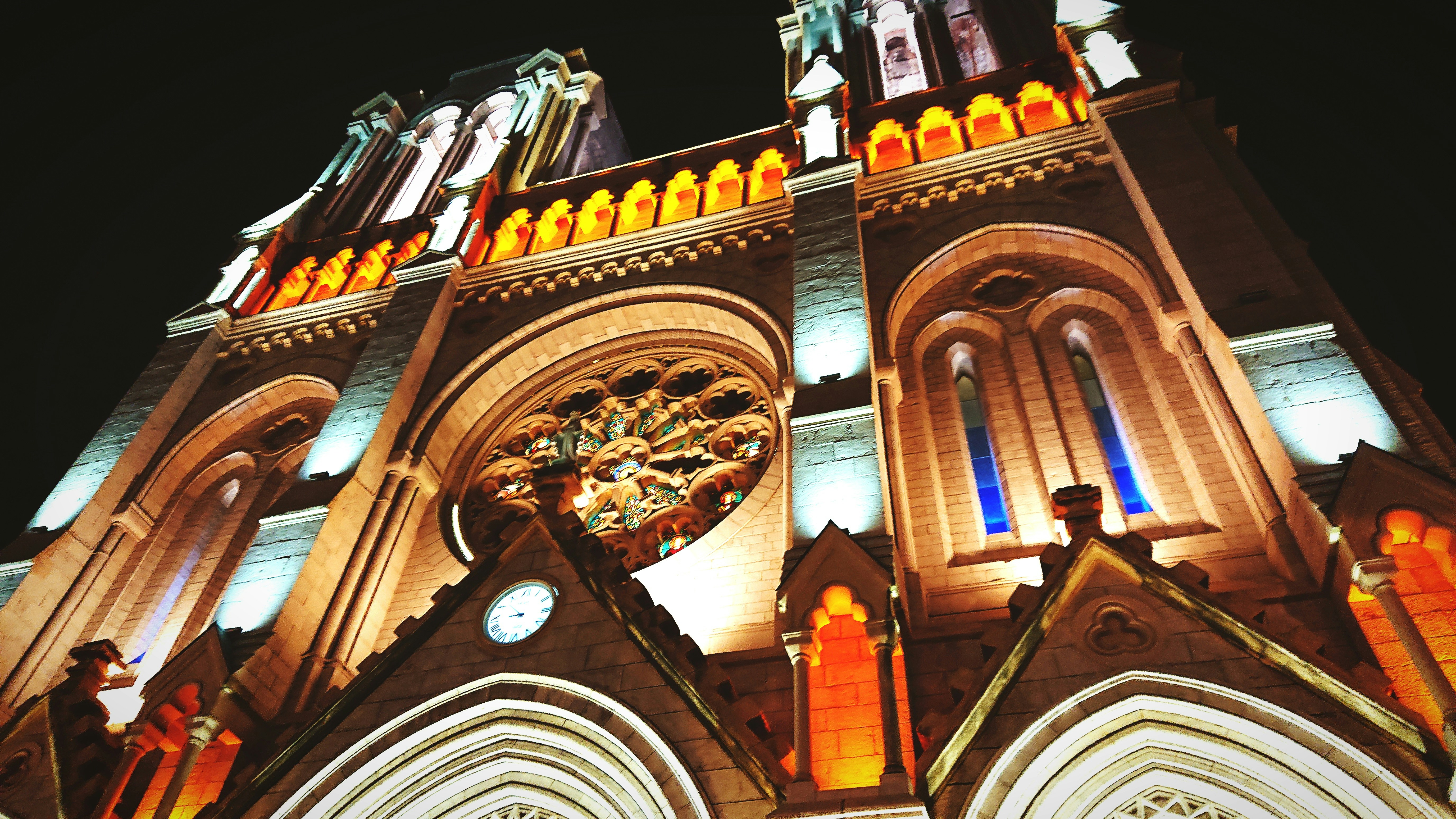 a large cathedral lit up at night with a clock, 