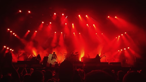 A vibrant scene of musicians playing traditional Turkish instruments on stage with red and white lighting.