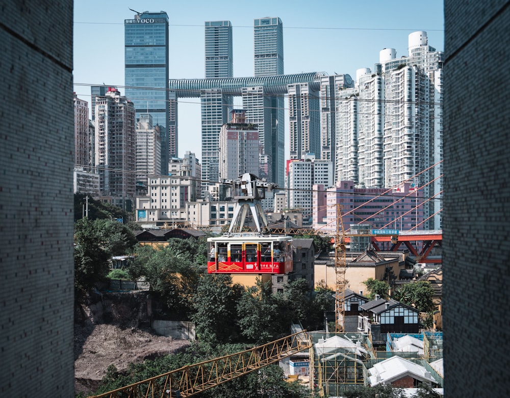 a red train traveling through a city next to tall buildings