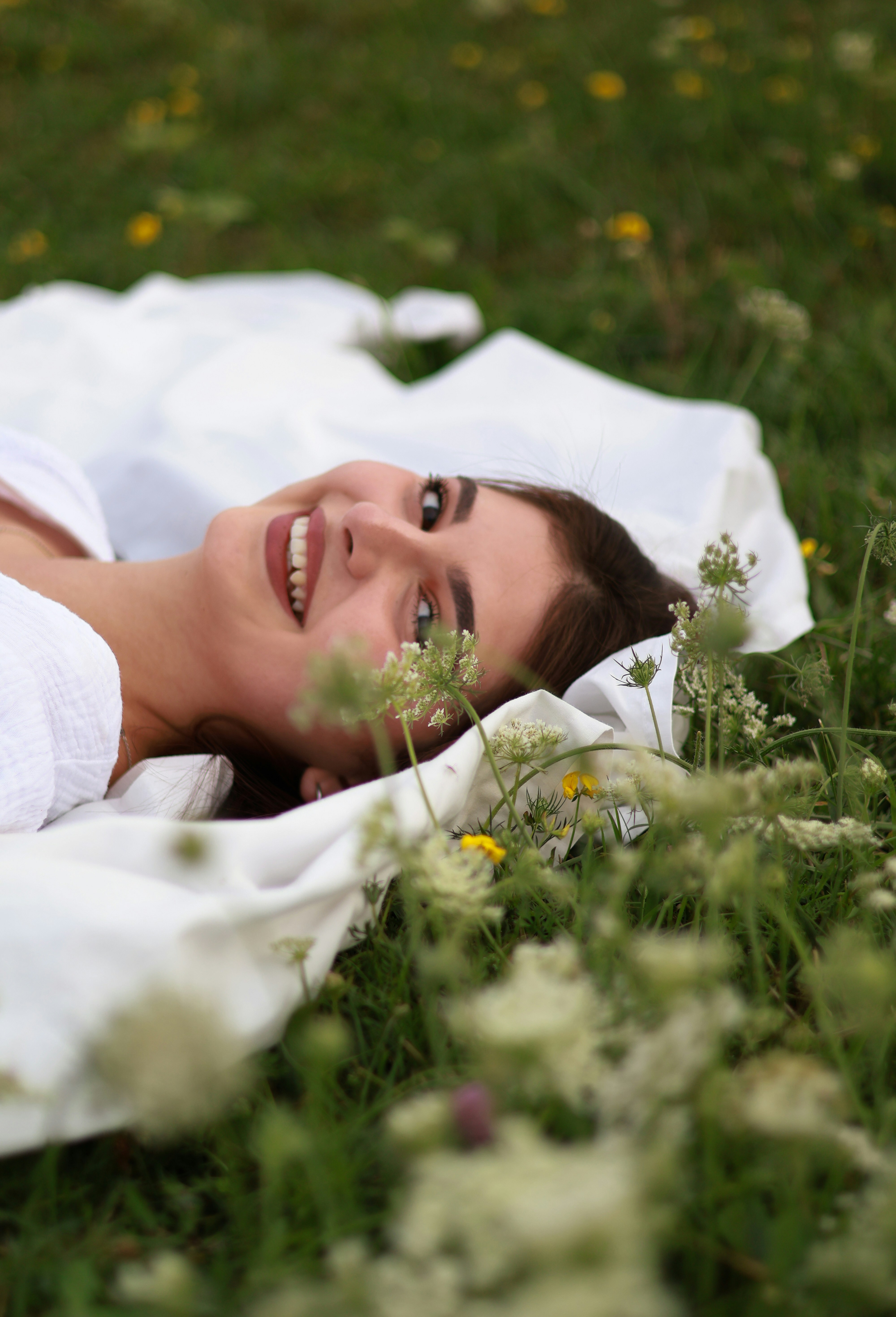 a woman laying on a blanket in a field of flowers
