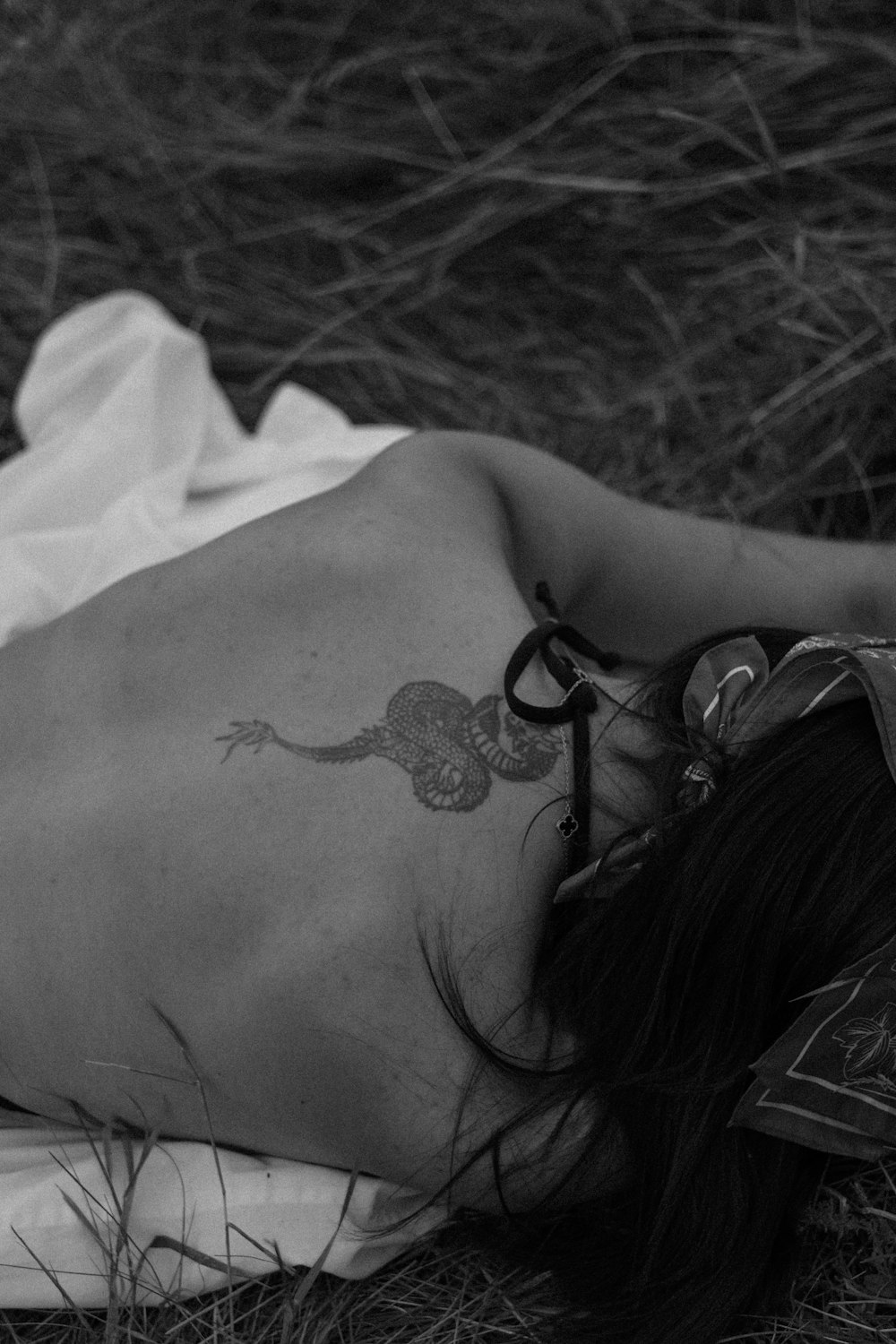 a woman laying on the ground with a tattoo on her back