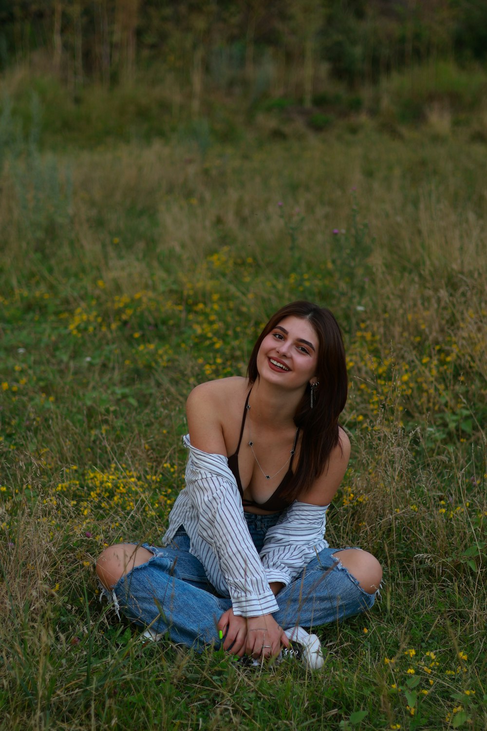 a woman sitting on the ground in a field