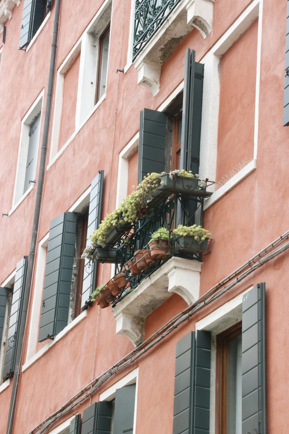 a pink building with green shutters and a balcony