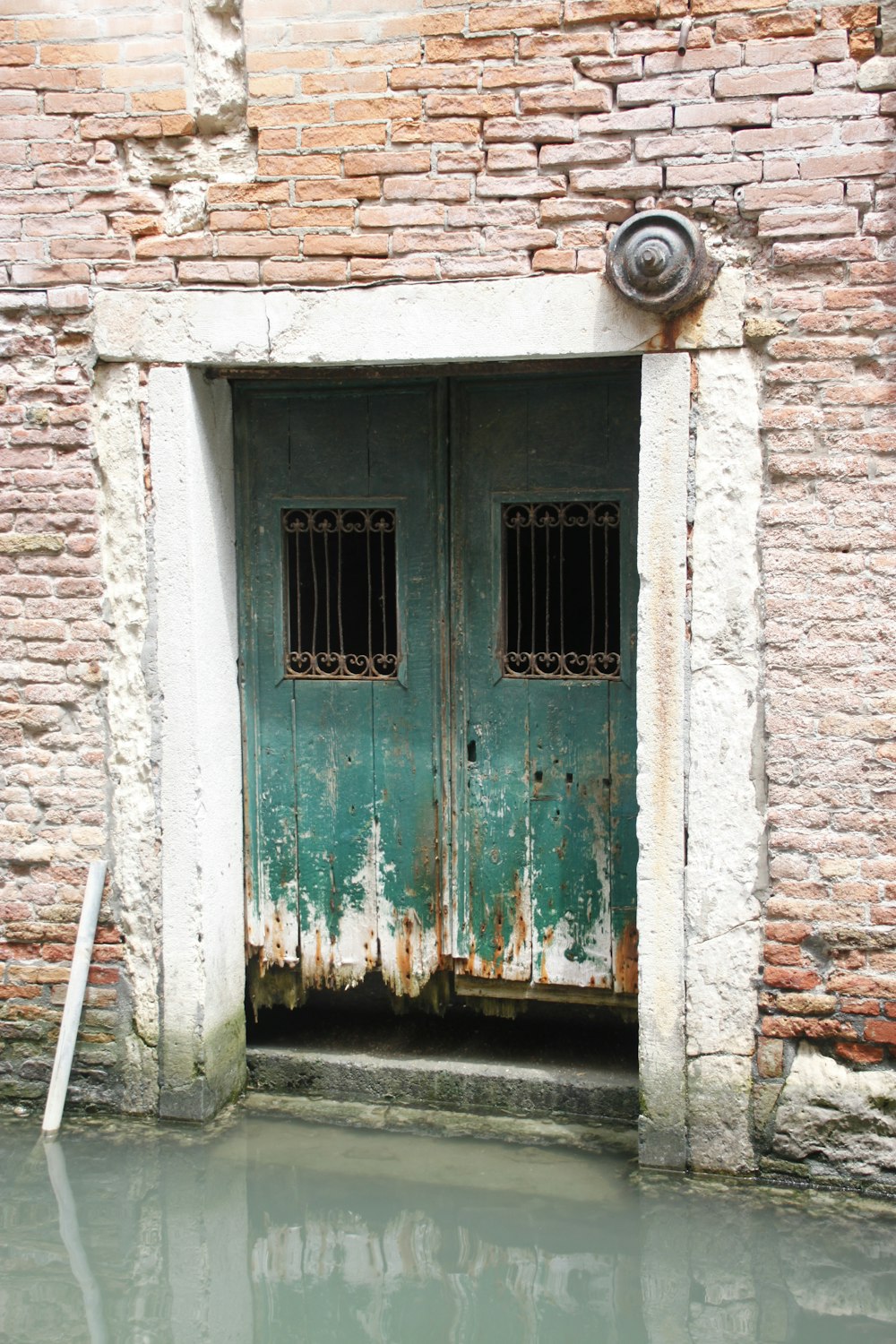 a green door in a brick wall next to a body of water