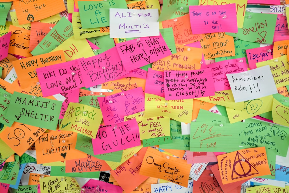 a pile of colorful post it notes on a wall