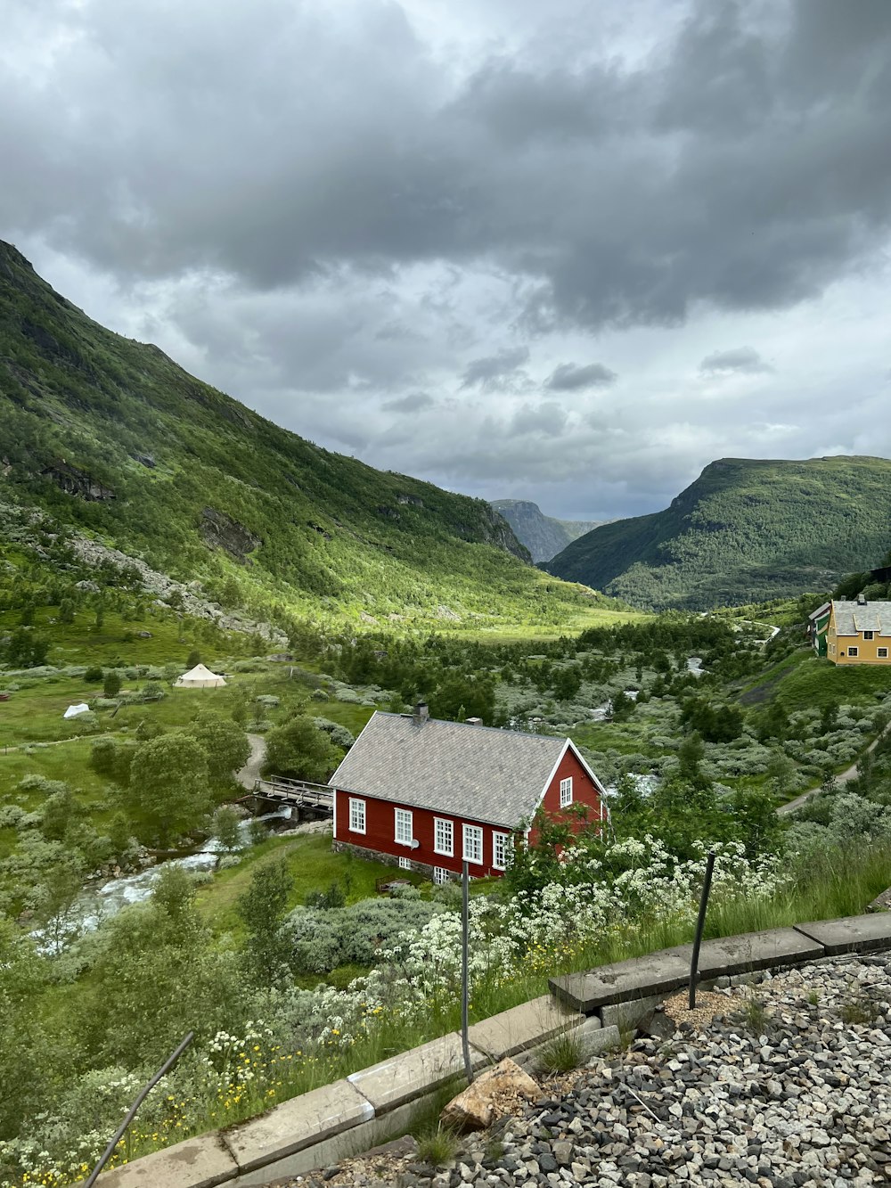 a red house sitting on top of a lush green hillside