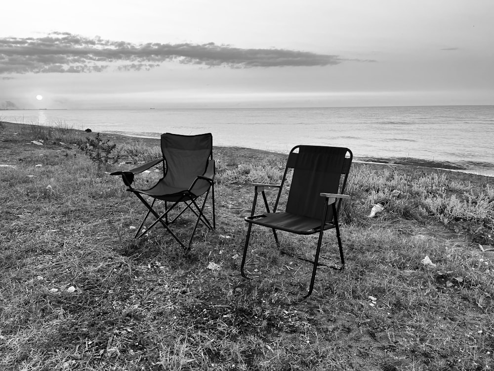 a couple of chairs sitting on top of a grass covered field