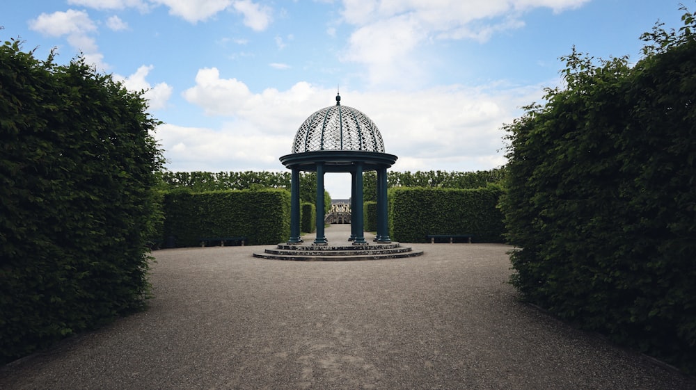 a gazebo surrounded by hedges in a park