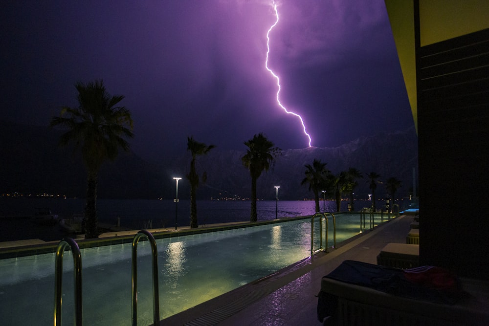 a lightning bolt strikes over a swimming pool at night