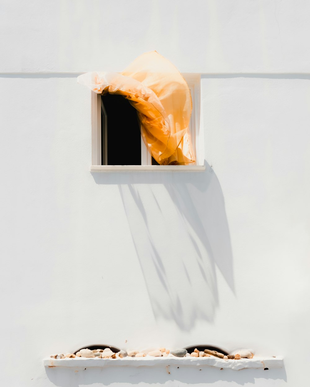 a white wall with a window and a plastic bag