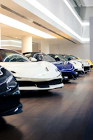 A lineup of cars in white, blue, and yellow colors inside the Showdrive showroom.