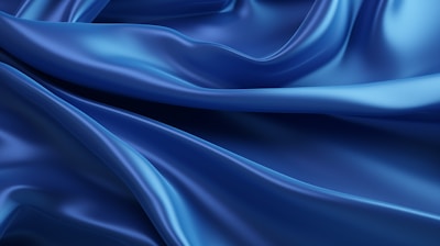 Deep blue, silky fabric with smooth waves and folds creating a luxurious, flowing texture.