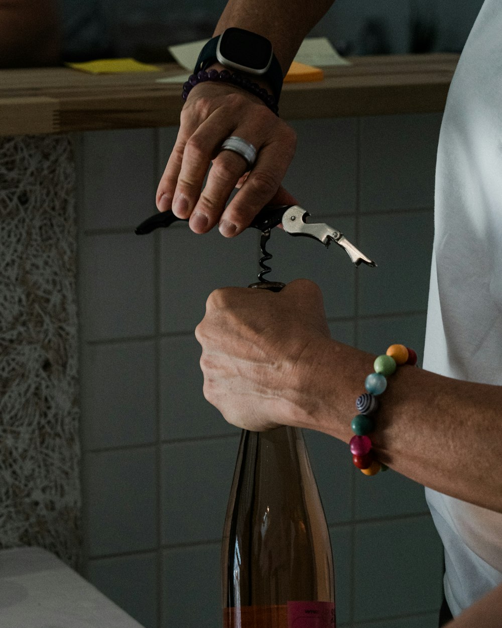 a person holding a wine bottle with a corkscrew attached to it