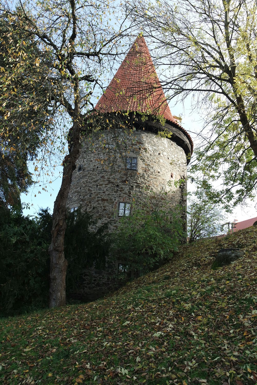 a stone tower with a red roof surrounded by trees