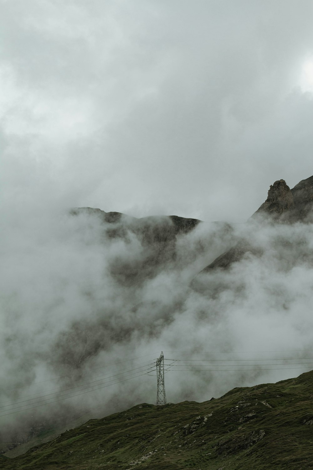 a mountain covered in fog with a telephone pole in the foreground