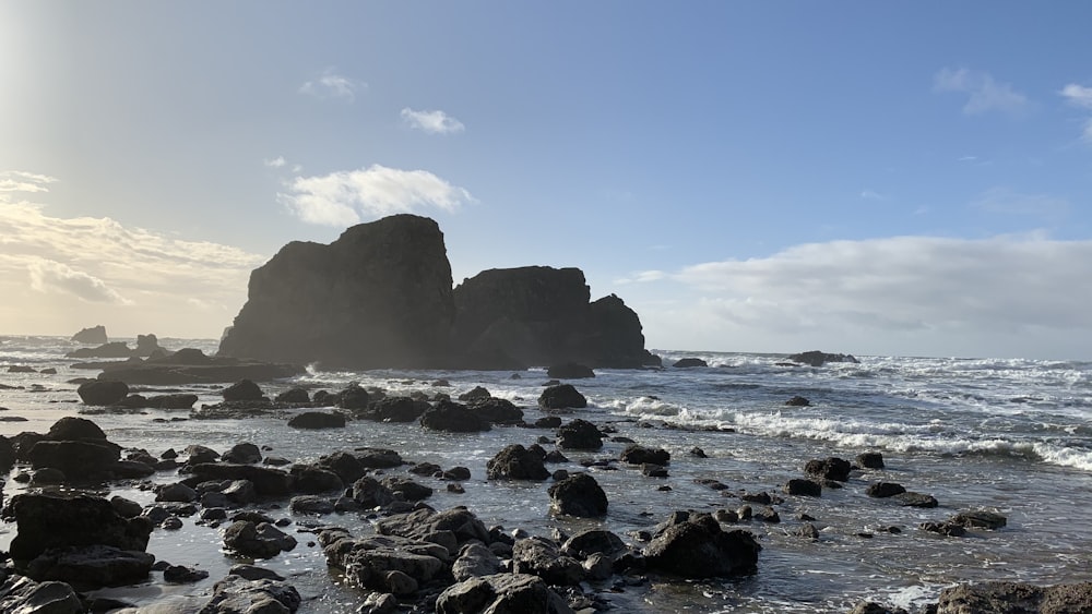 a beach with rocks and water on a sunny day