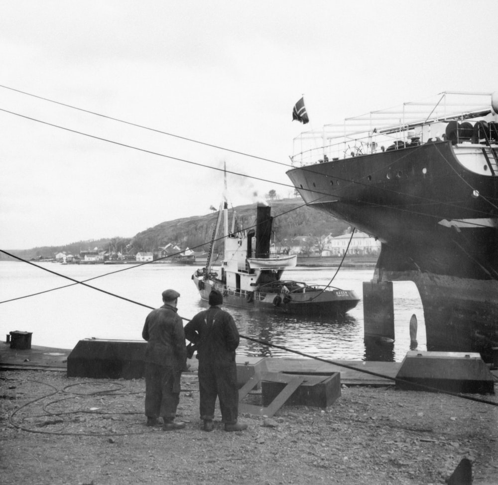 a couple of men standing next to each other near a boat