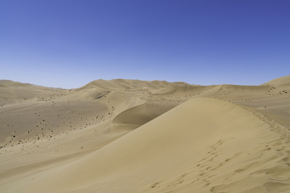 a desert landscape with sand dunes and a blue sky