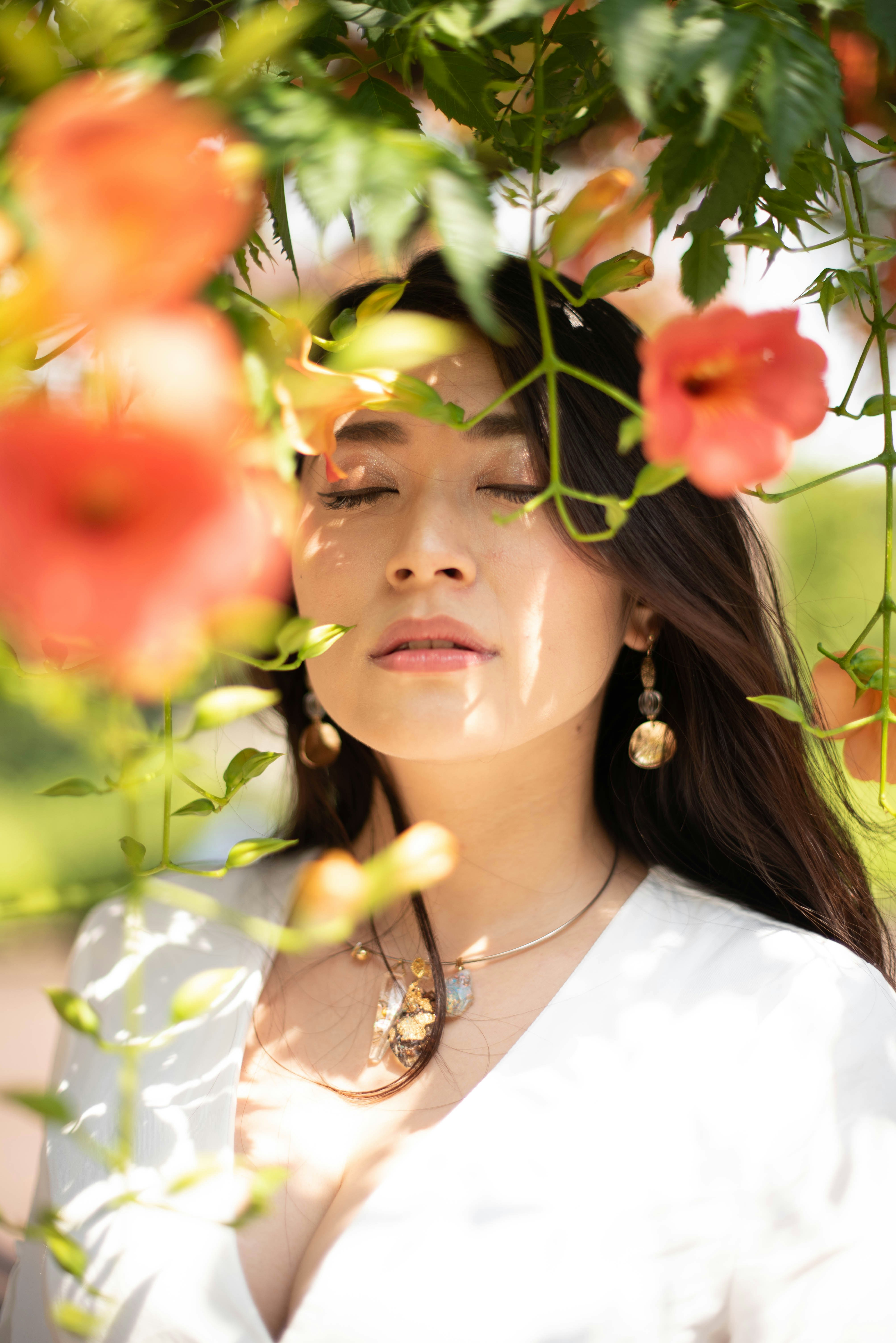a woman with her eyes closed standing under a tree