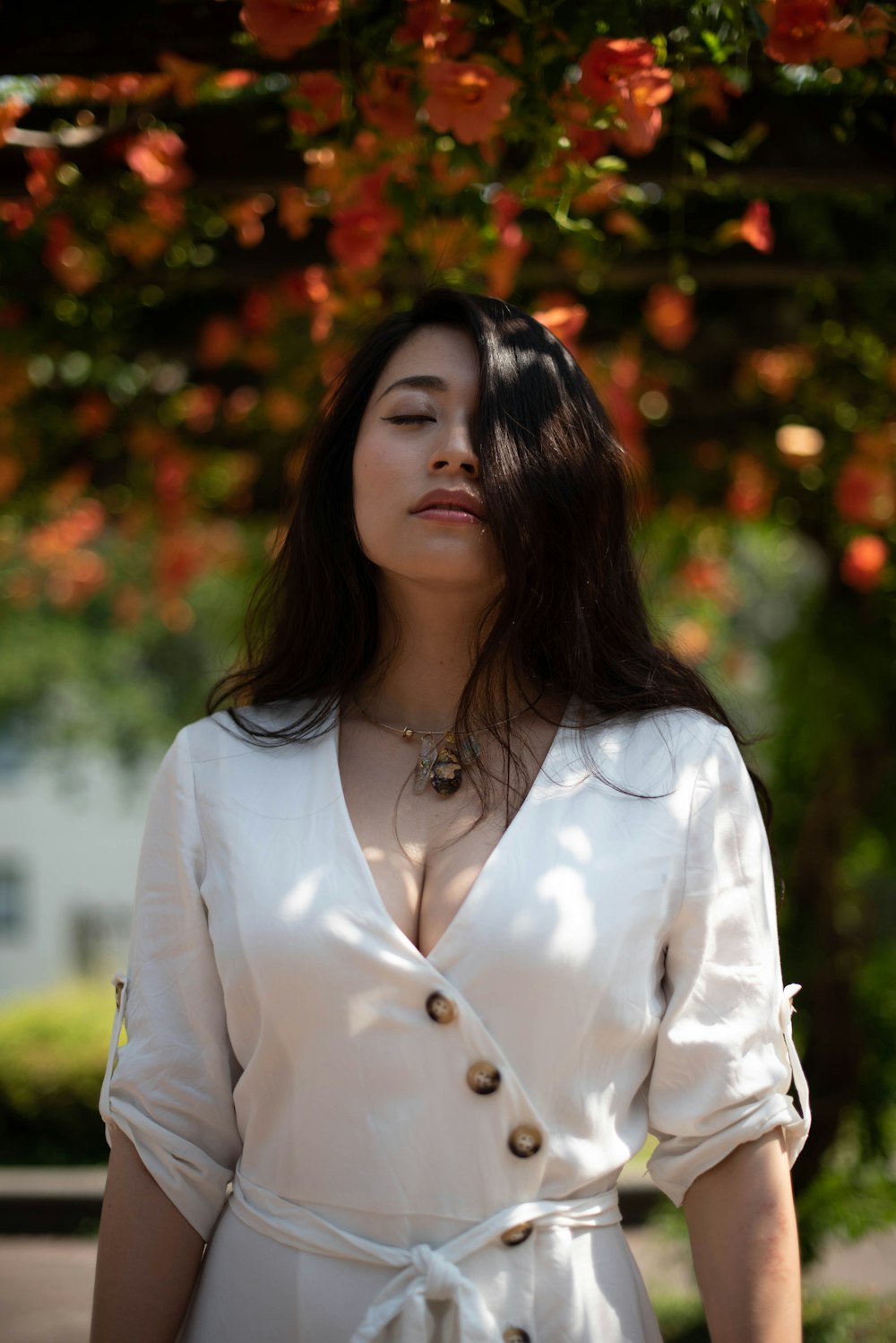 a woman standing under a tree with her eyes closed