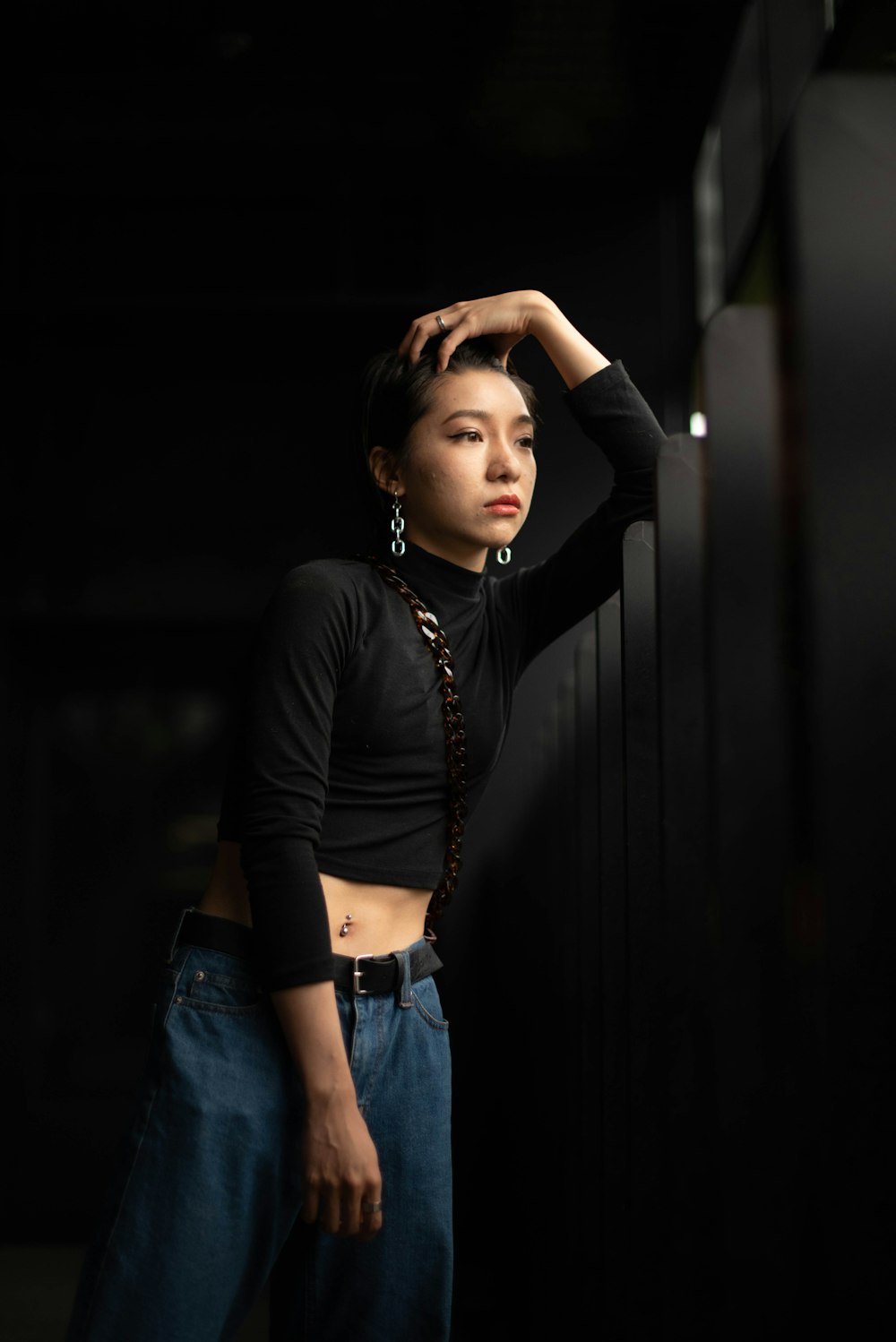 a woman leaning against a wall with her hand on her head