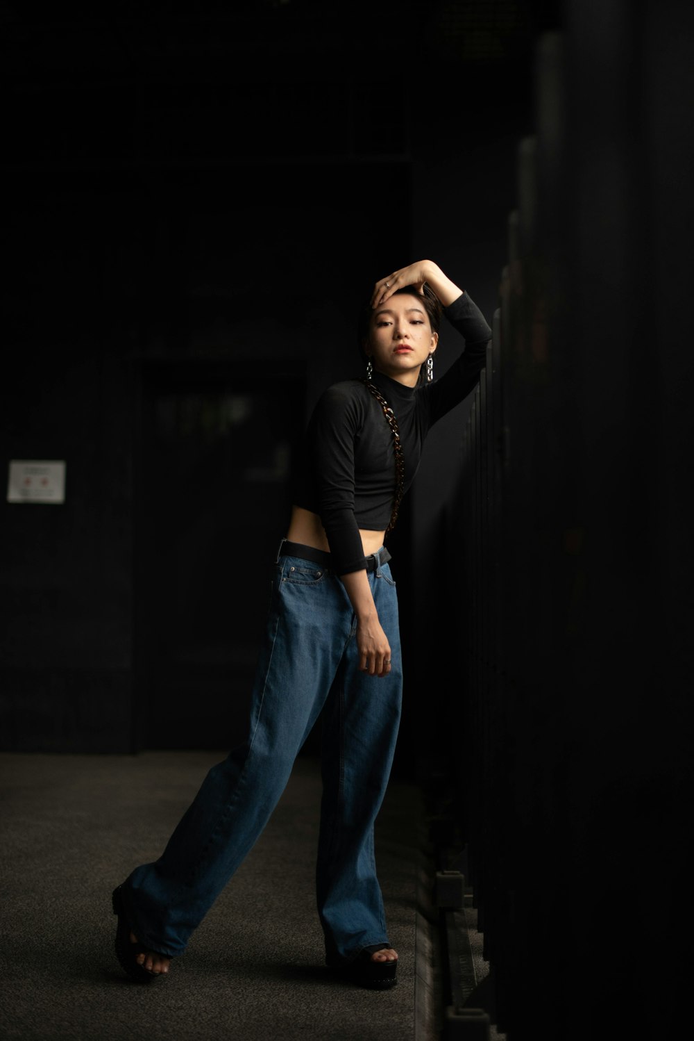 a woman leaning against a wall with her hands on her head