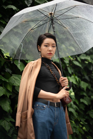 A confident businessperson standing under an umbrella in a storm, symbolizing resilience through challenges.