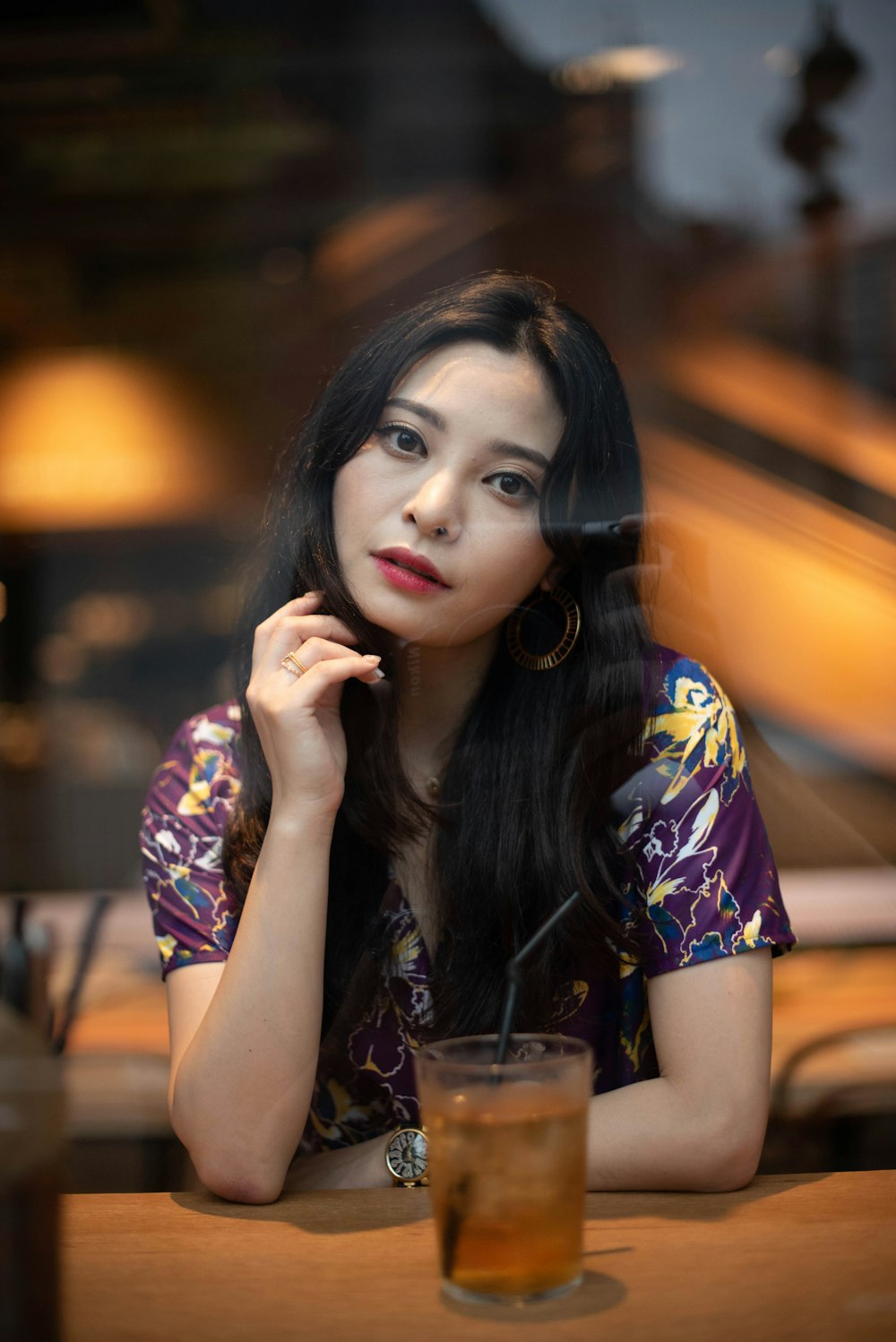 a woman sitting at a table with a drink