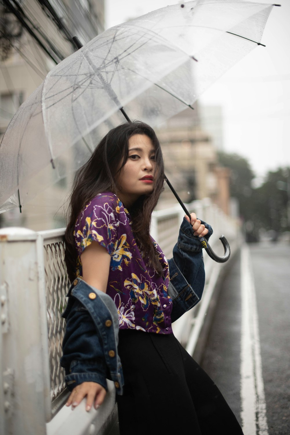 a woman holding an umbrella while sitting on a ledge