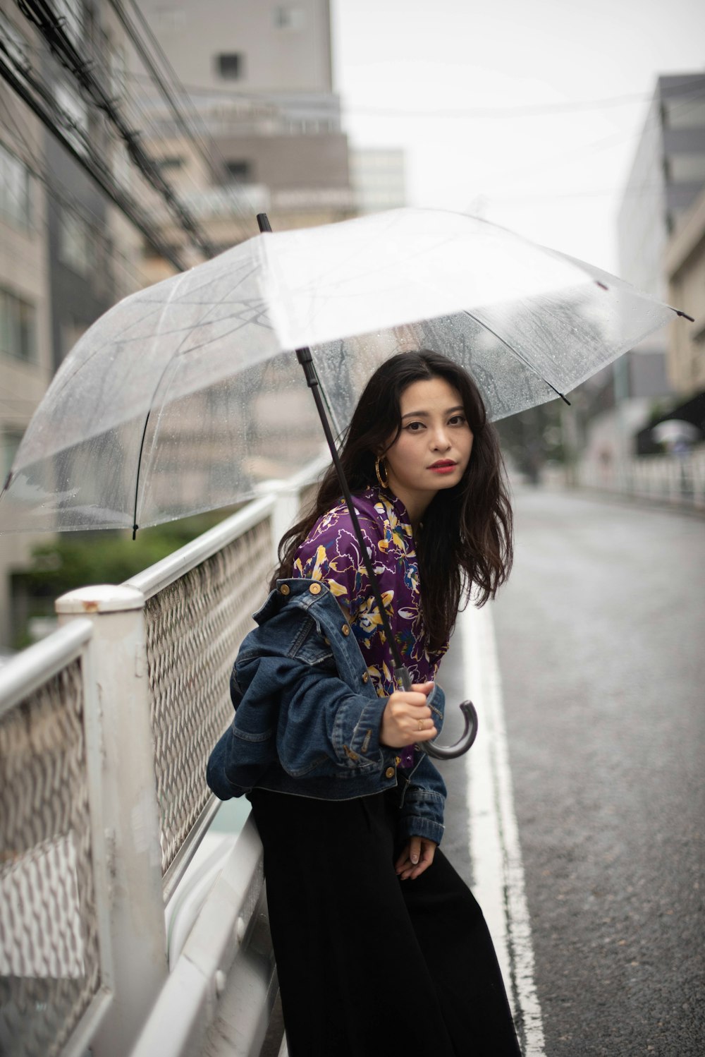 a woman standing on a bridge holding an umbrella