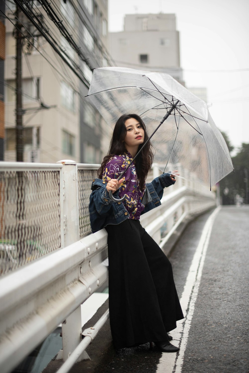 a woman standing on a bridge holding an umbrella