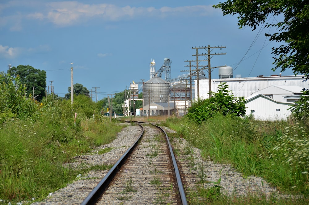 a train track with a factory in the background