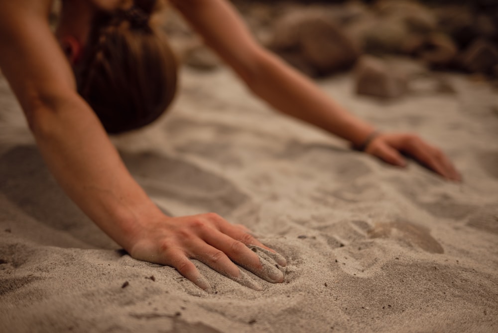 a person reaching for something in the sand