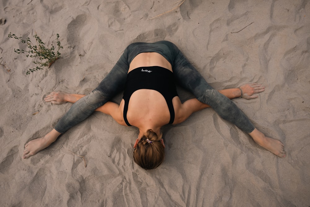 a woman laying on the sand with her back to the camera