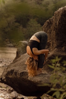 a woman is doing a handstand on a rock