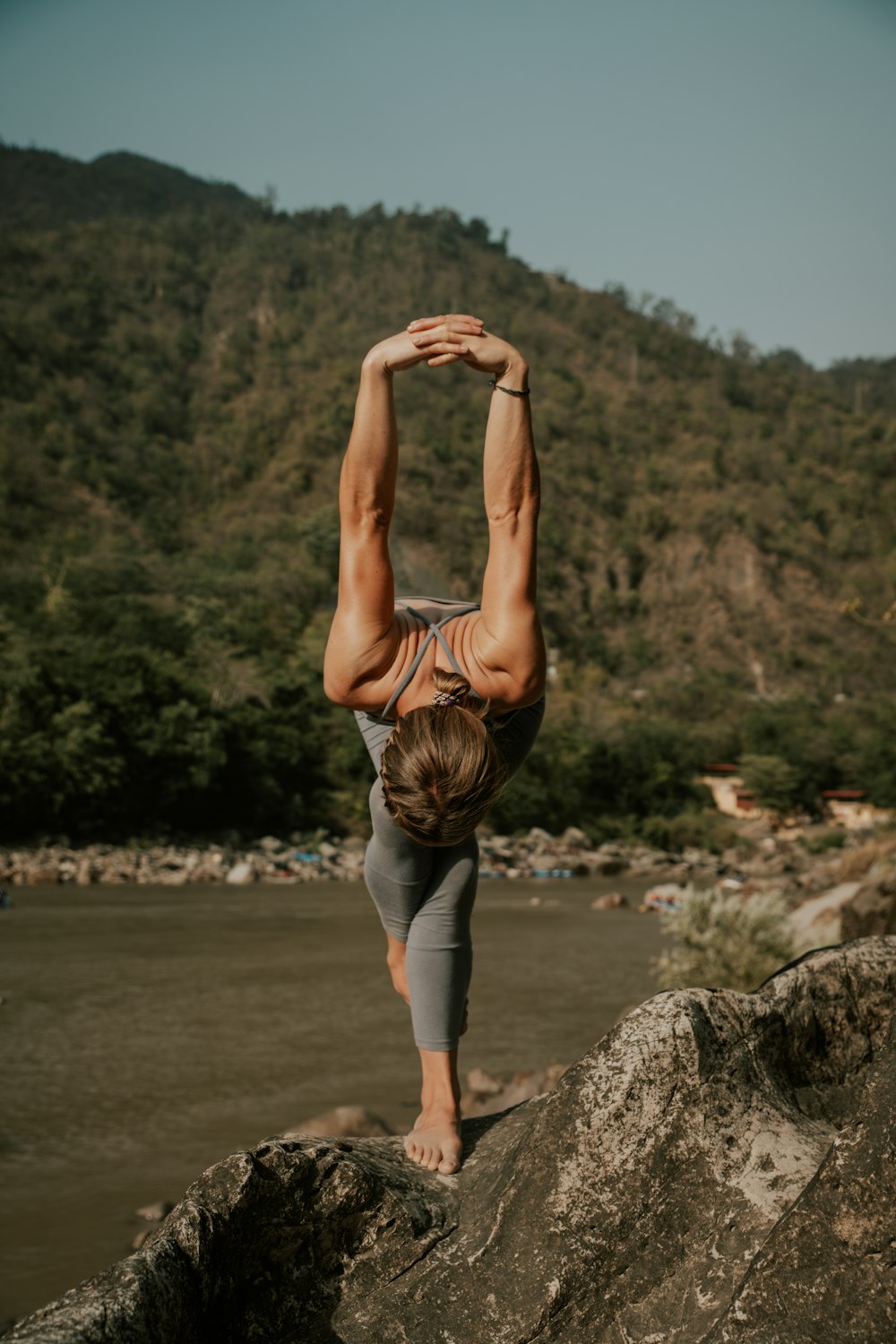 a woman doing a handstand on top of a rock