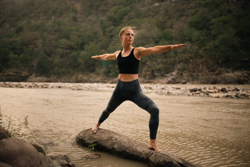 a woman standing on a log in a river