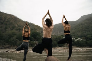 A joyful group practicing yoga outdoors with mountains in the background, embodying balance and fitness.